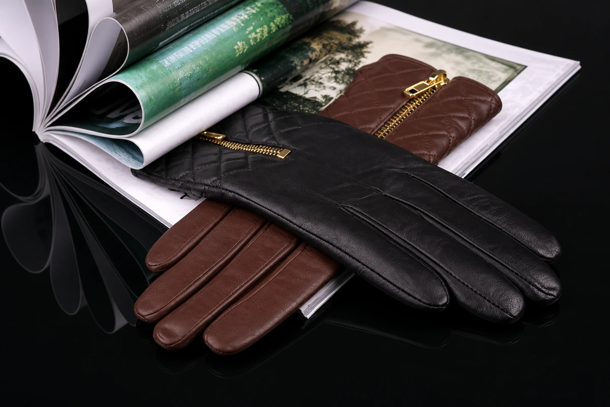 Black and brown leather gloves with gold zippers resting on an open book
