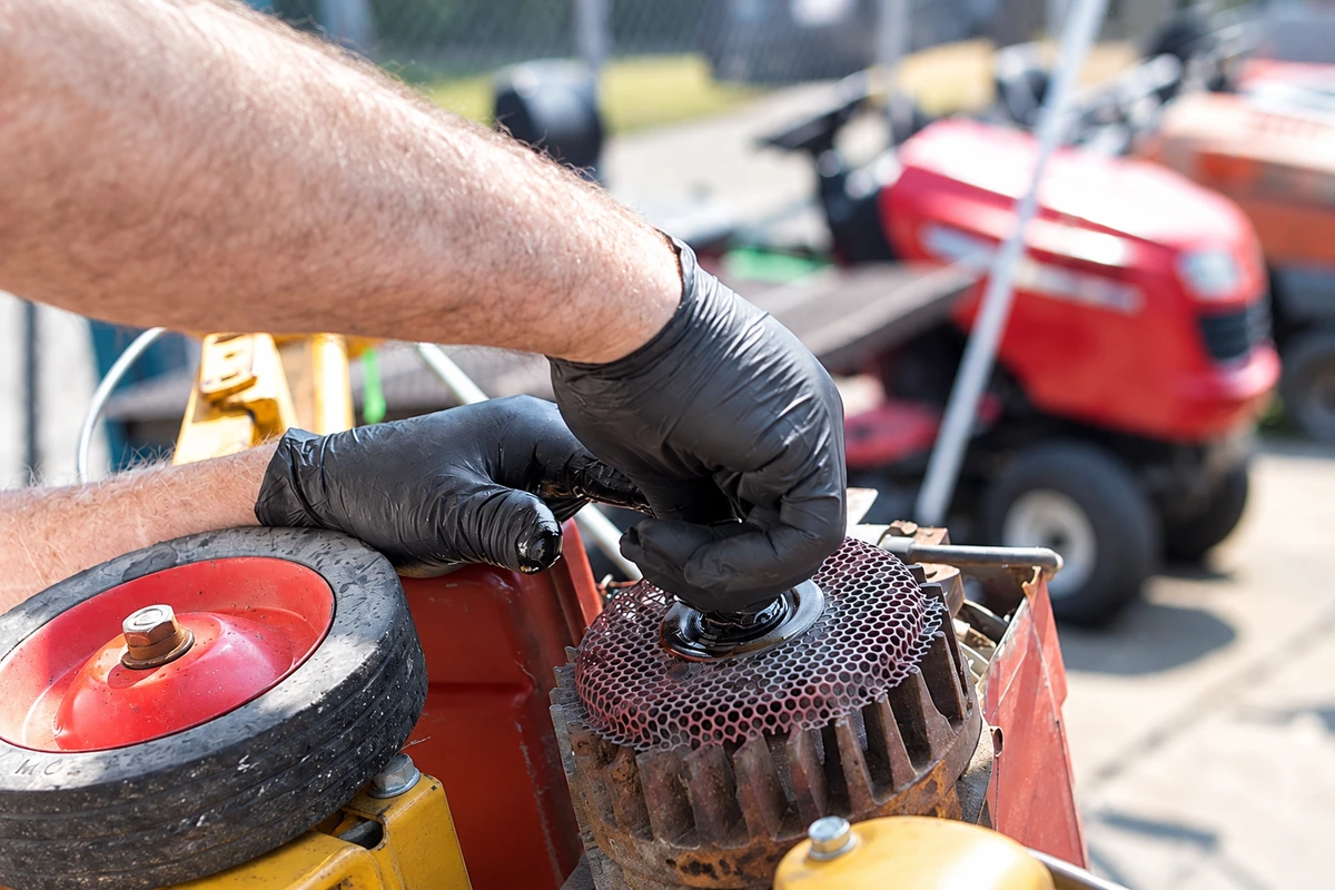 Black disposable gloves worn while servicing outdoor power equipment