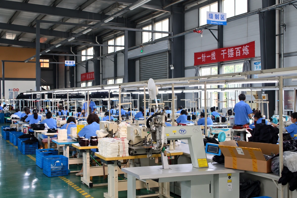 Workers at sewing stations on a glove production floor