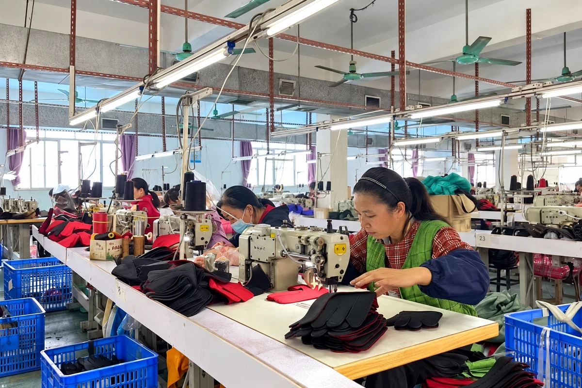 Workers sewing gloves at rows of production workstations