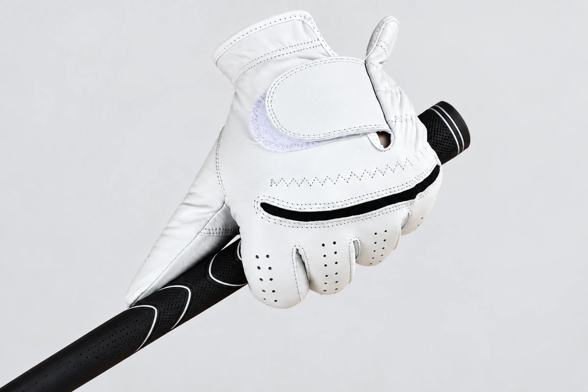 White golf glove gripping a black club handle