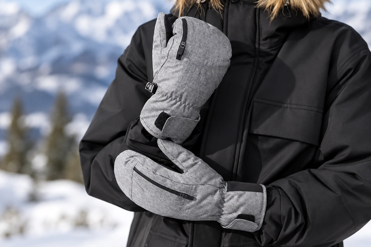 Person wearing gray winter mittens with zippered backs and adjustable cuffs