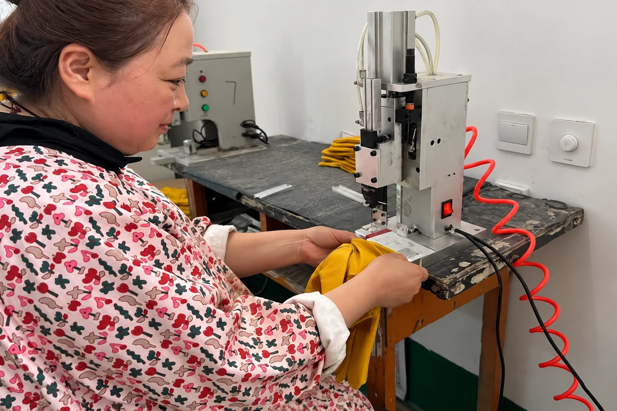 Worker handling a yellow glove at a production machine