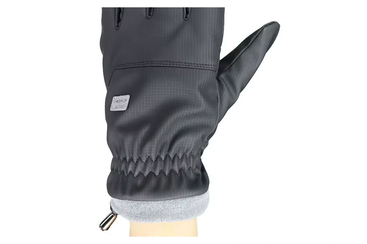 Close-up of a gray glove with a small stitched label above a gathered cuff
