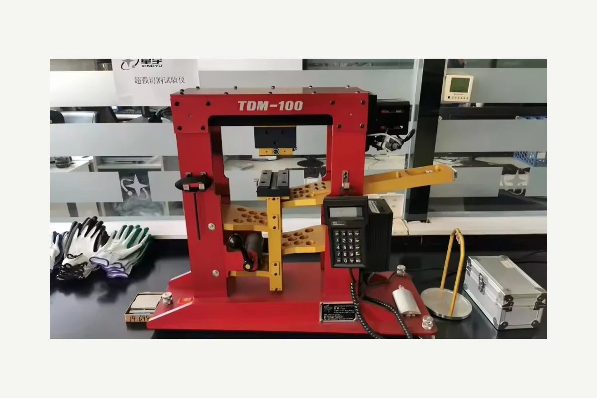Red laboratory testing machine with a control panel and sample clamps