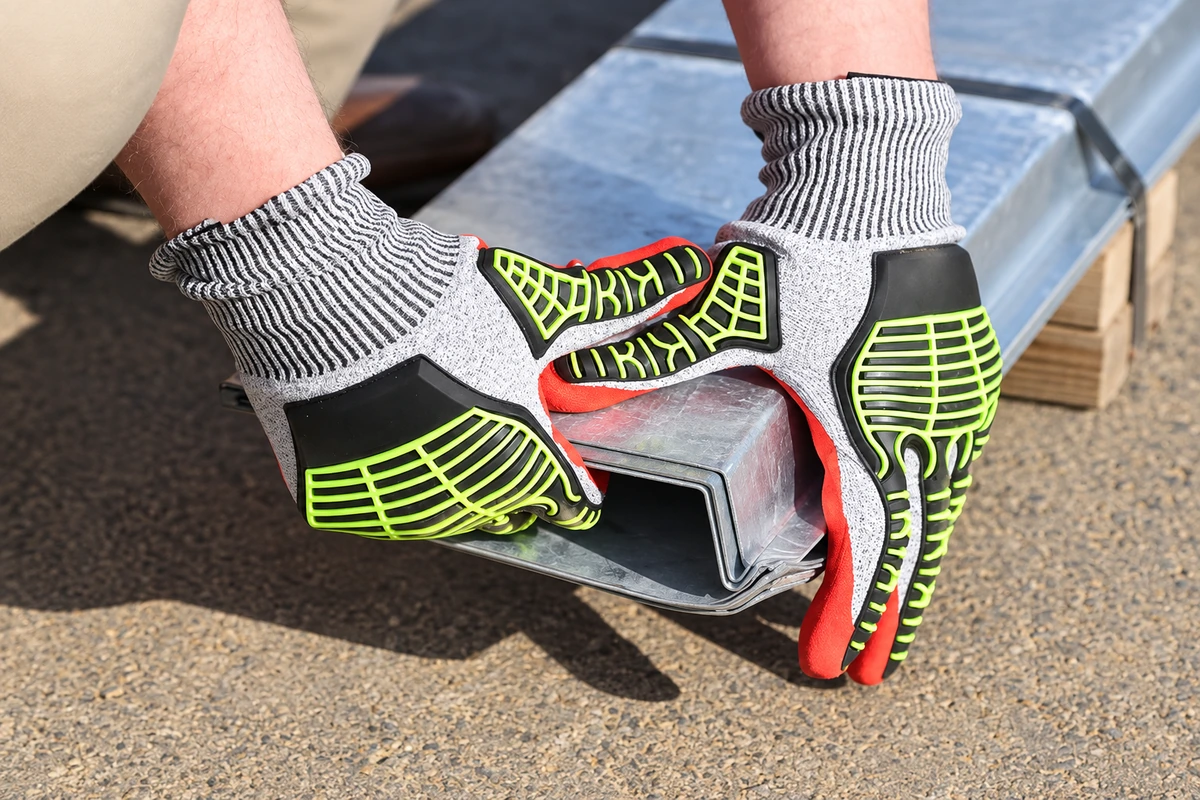 Gray and lime reinforced gloves holding a metal section