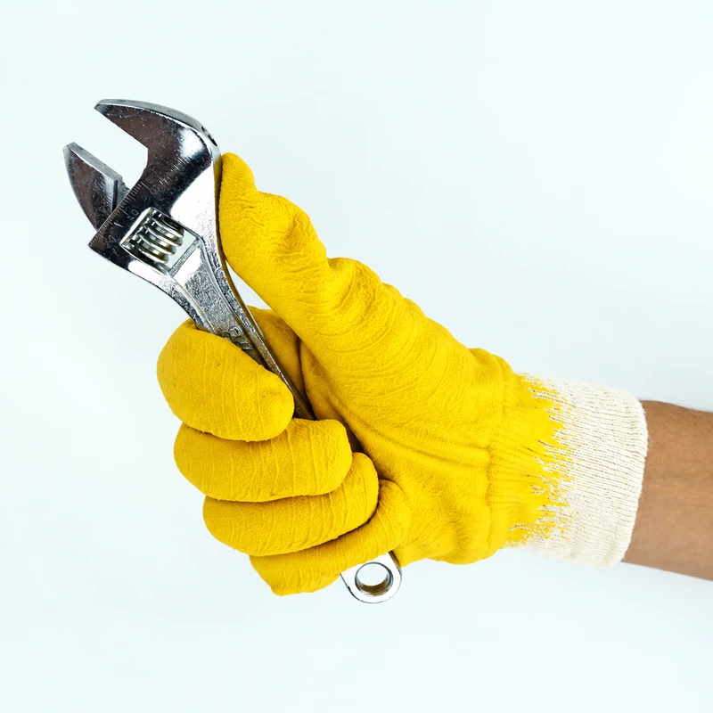 Yellow coated glove gripping an adjustable wrench