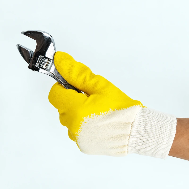 Side view of a yellow coated glove holding a wrench