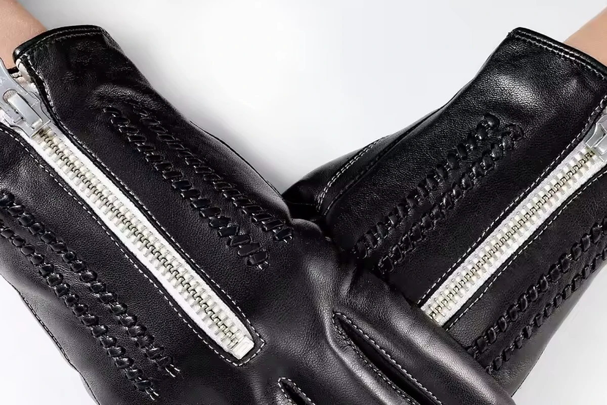 Close view of black leather glove cuffs, stitching and zipper construction