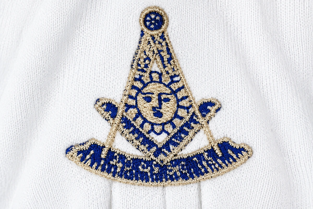 Close-up of blue and gold embroidery on white glove fabric