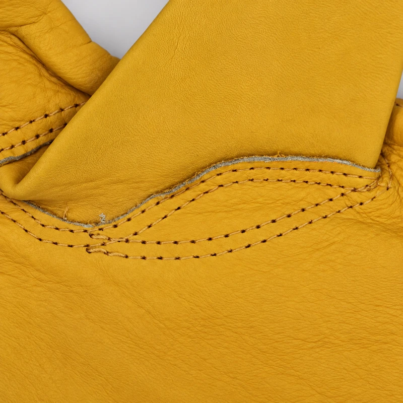 Curved rows of stitching around a yellow leather glove thumb