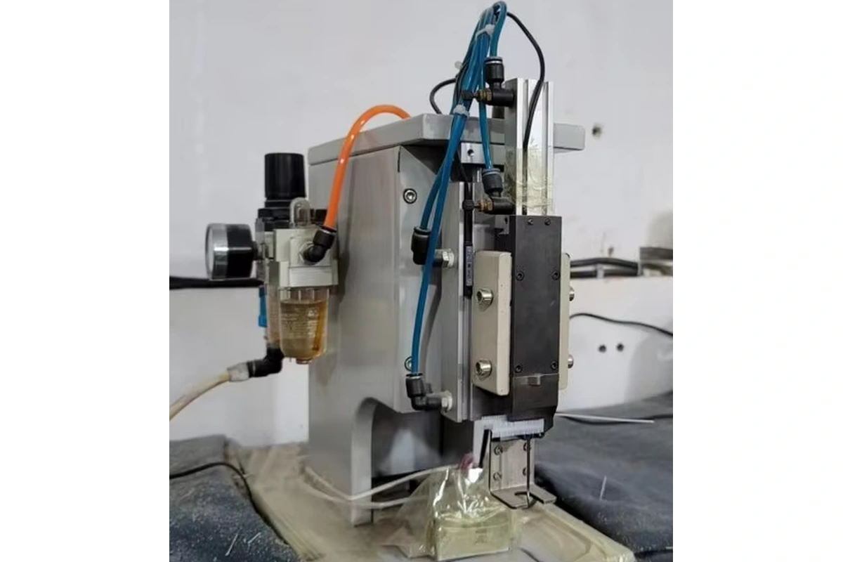 Cutting machine positioned over layers of gray fabric