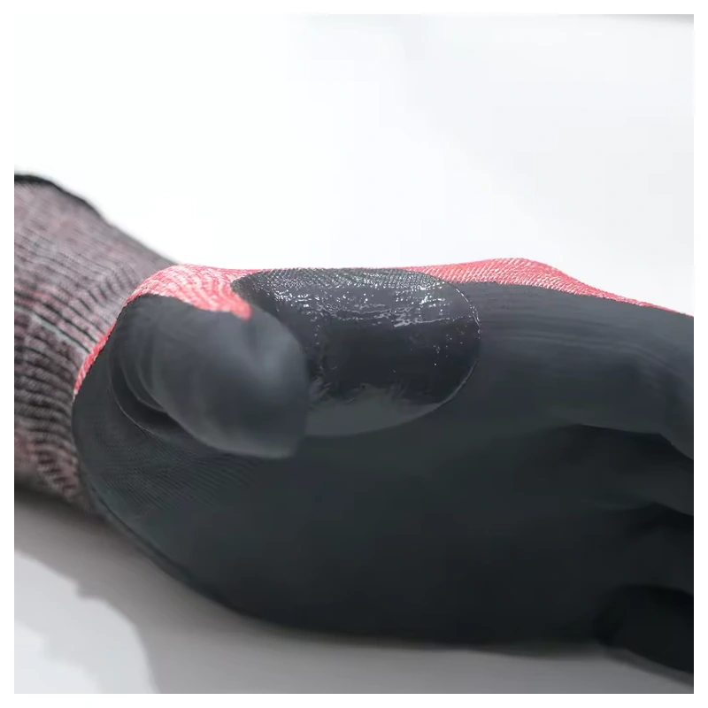 Close-up of the black coating around the thumb web of a red-gray glove