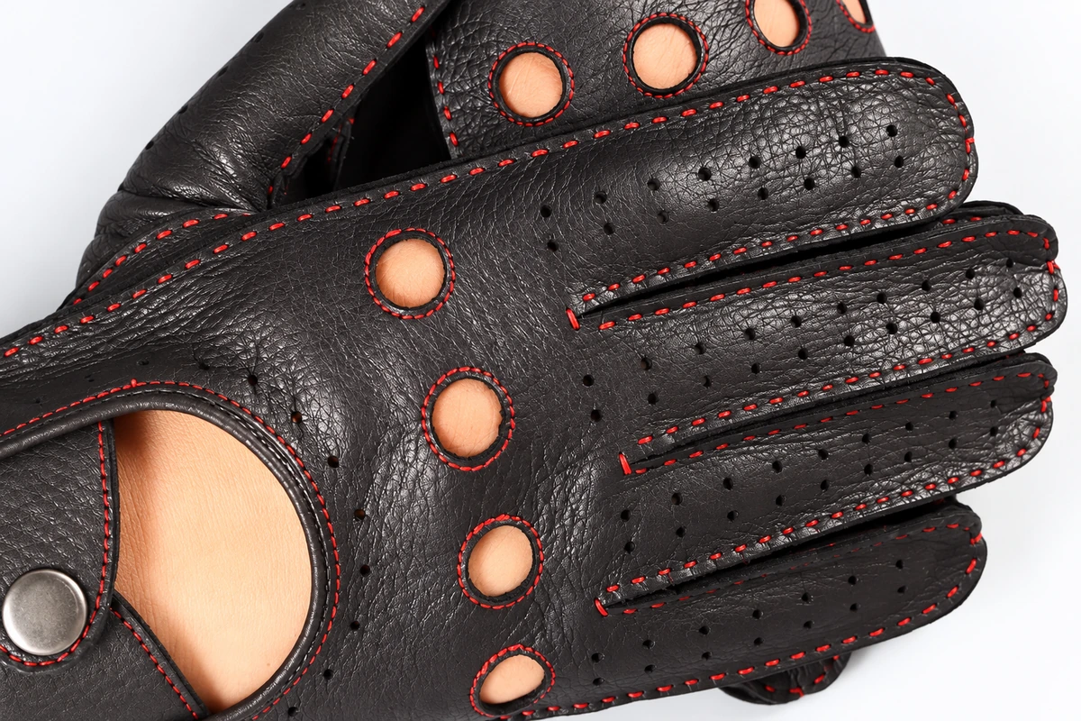 Perforated black driving gloves with red stitching and open knuckles