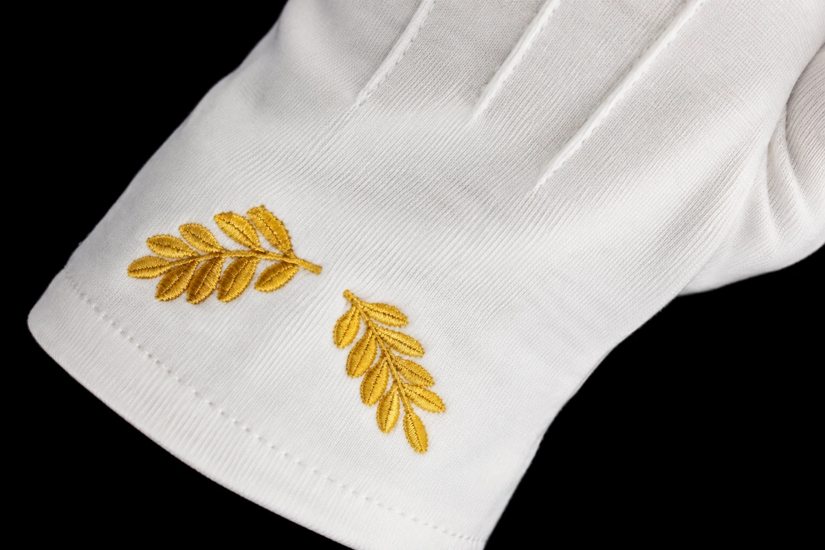 Close view of gold leaf embroidery on a white glove cuff