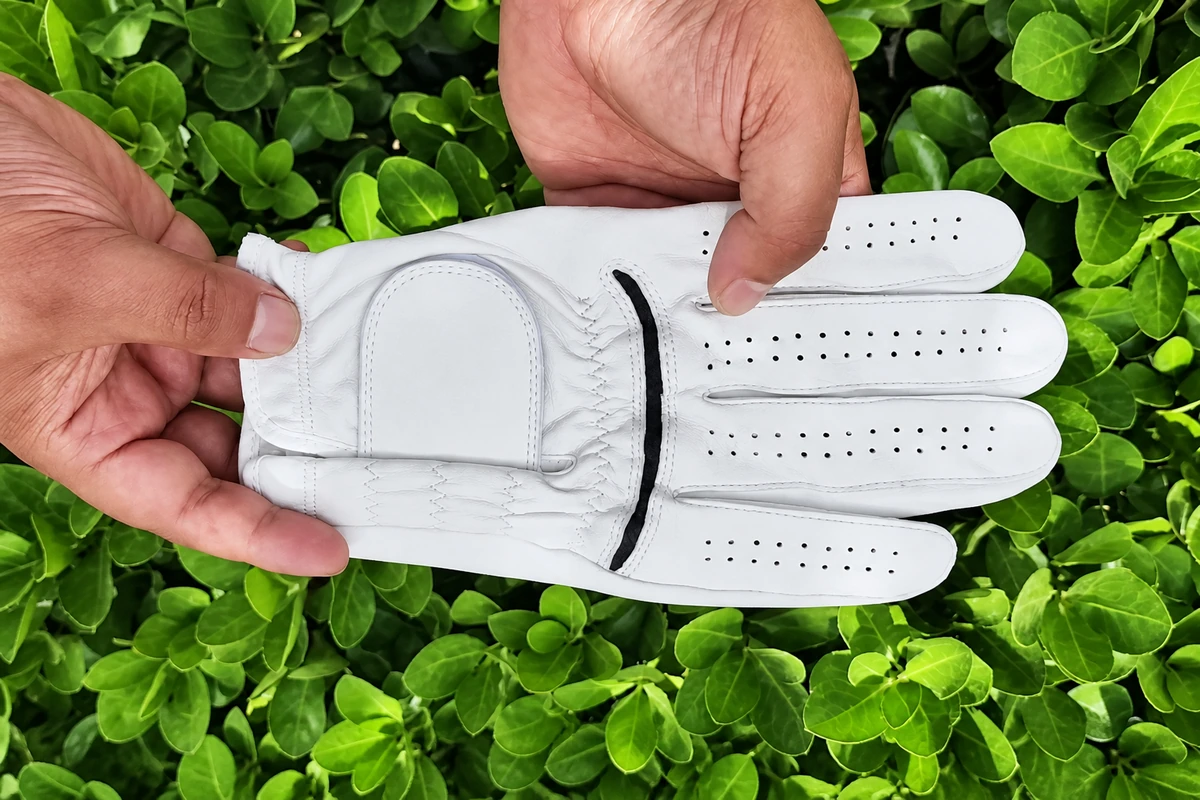 Hands holding a white golf glove for inspection