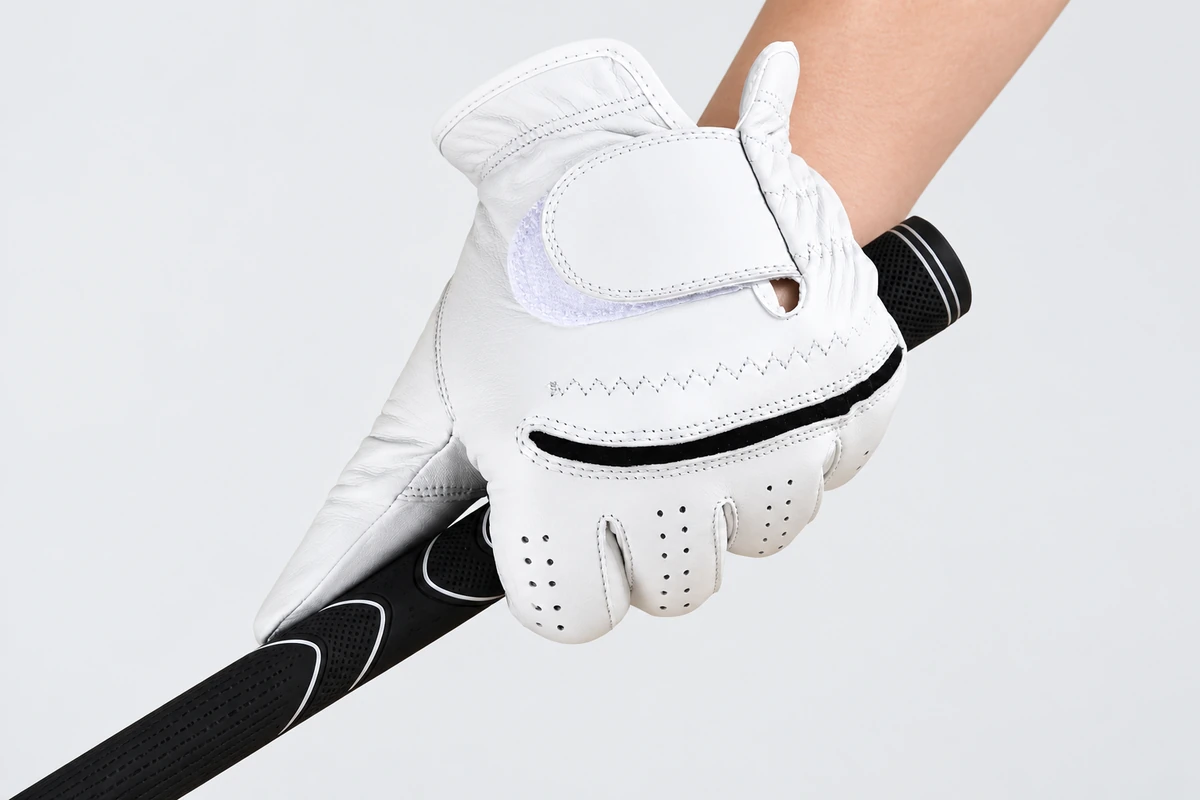 White golf glove gripping a black golf club handle