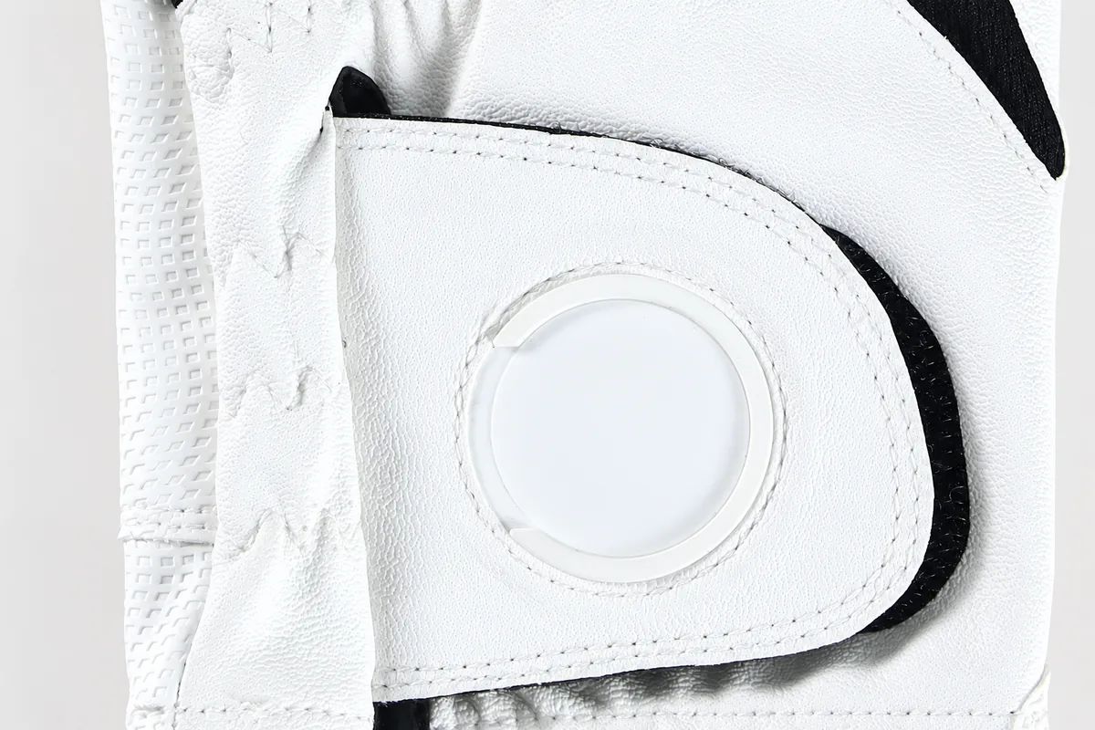 White golf glove wrist closure with a round inset and black hook-and-loop edge