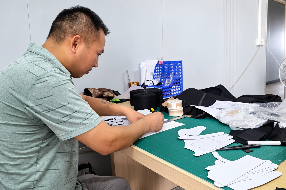 Worker drawing glove patterns at a workbench