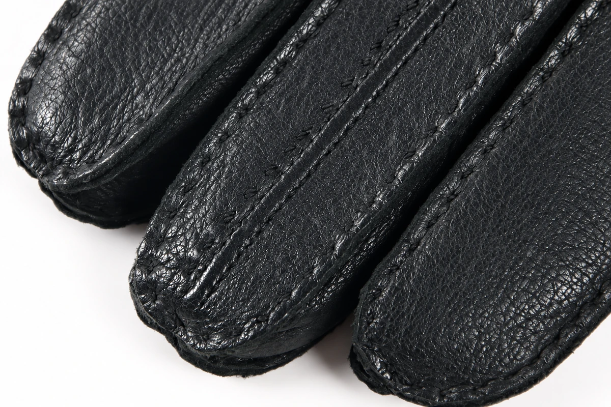 Black leather glove fingertips with visible stitched seams