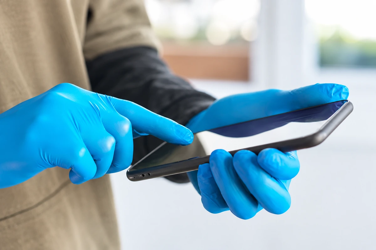 Blue disposable gloves holding and touching a phone