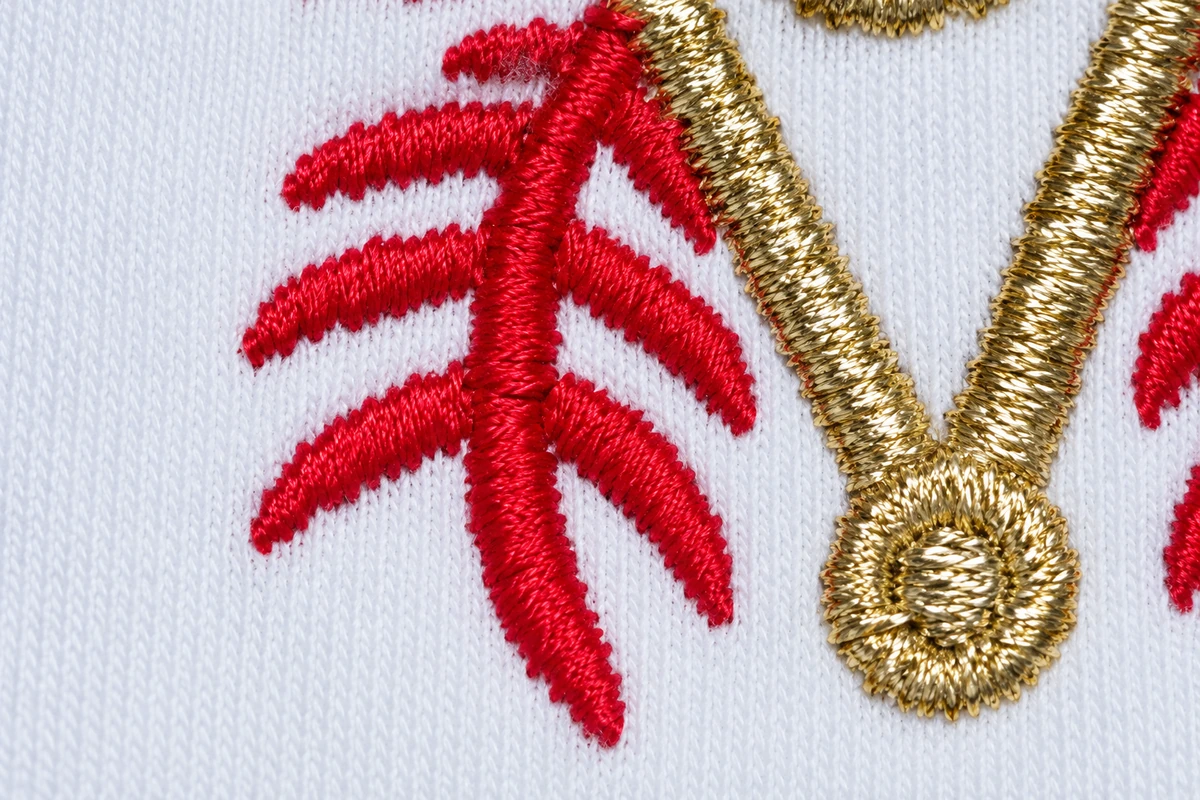 Red and gold embroidered threads on white glove fabric