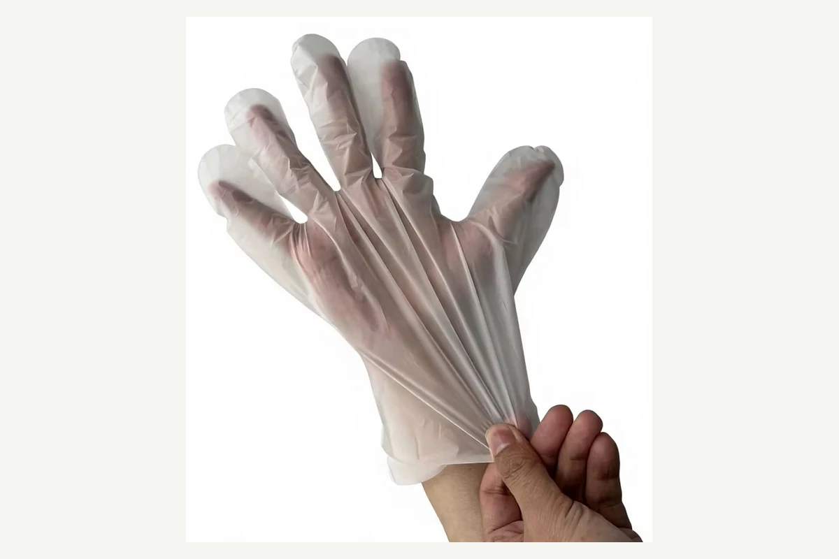 Clear film glove stretched at the cuff while being pulled onto a hand
