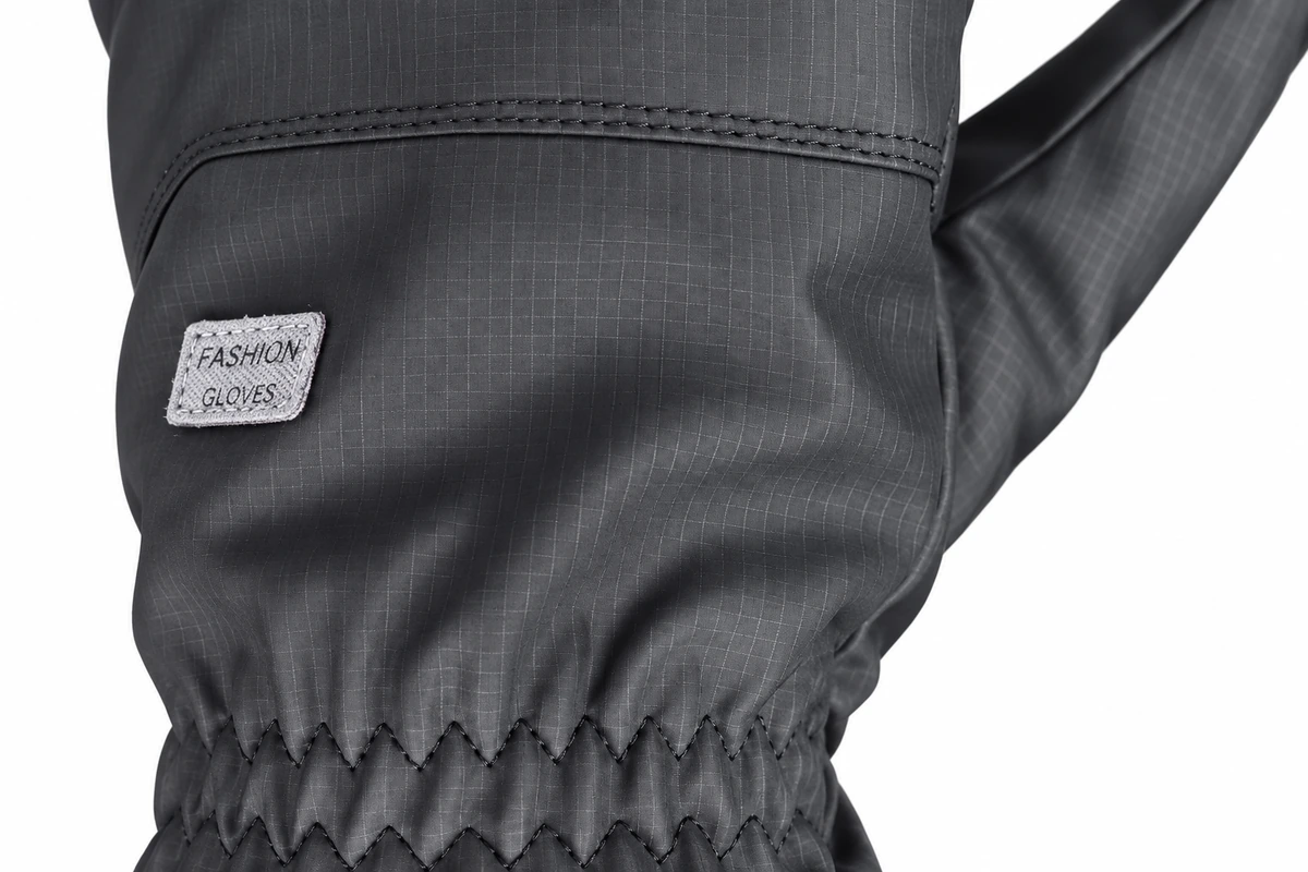Small sewn label on a gray glove back above a gathered wrist