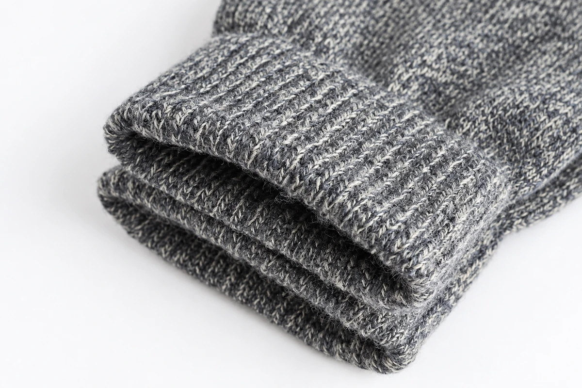 Gray marled knitted glove showing ribbed cuff and yarn texture