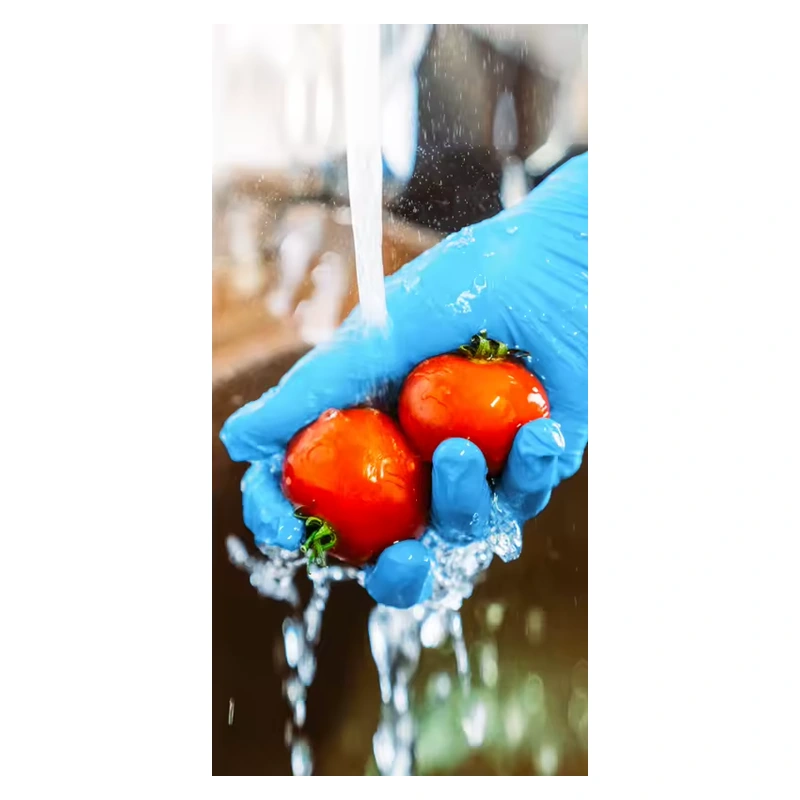 Blue disposable glove holding two tomatoes under running water